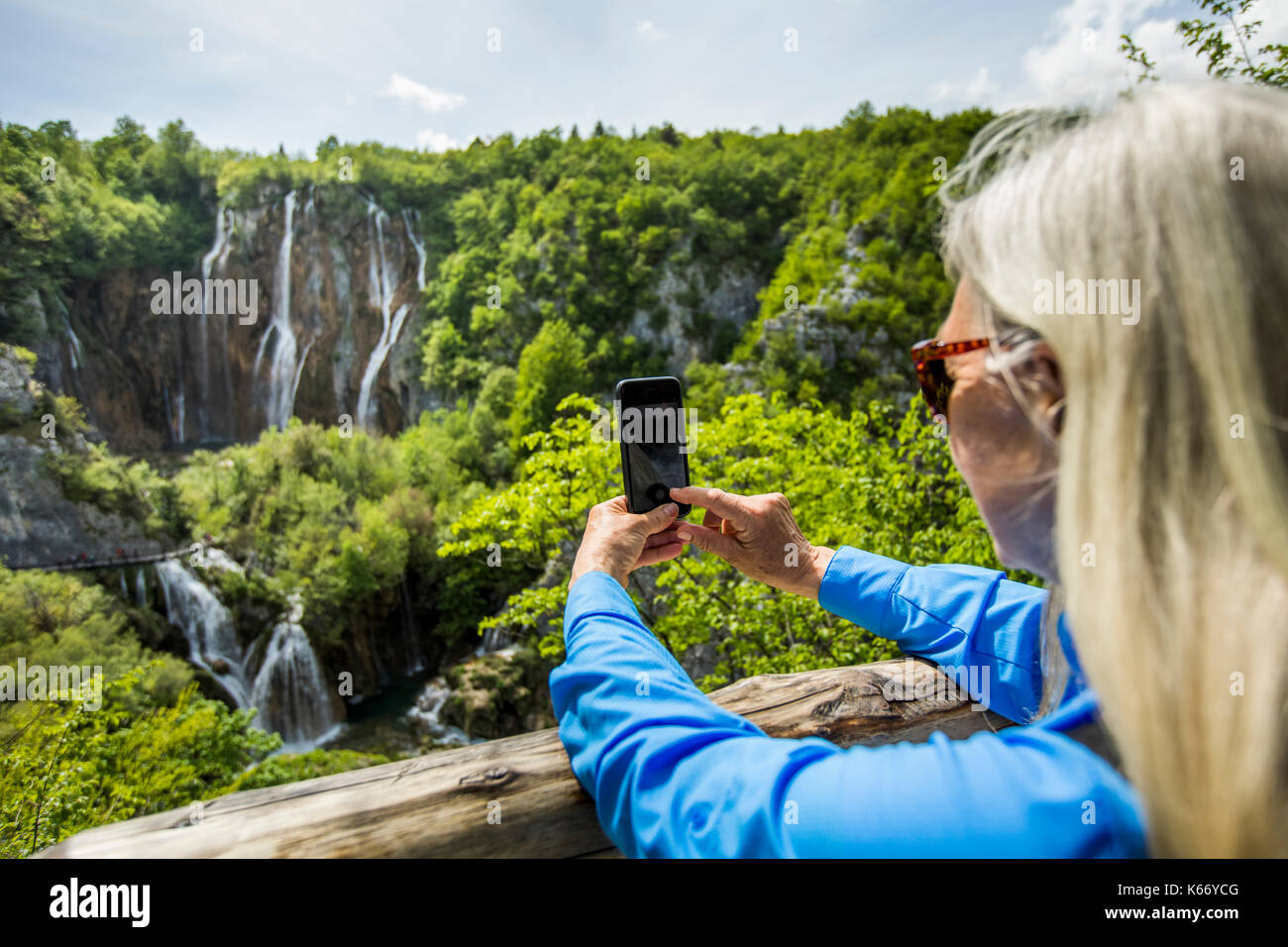 Older Caucasian woman photographing waterfalls with cell phone Stock Photo
