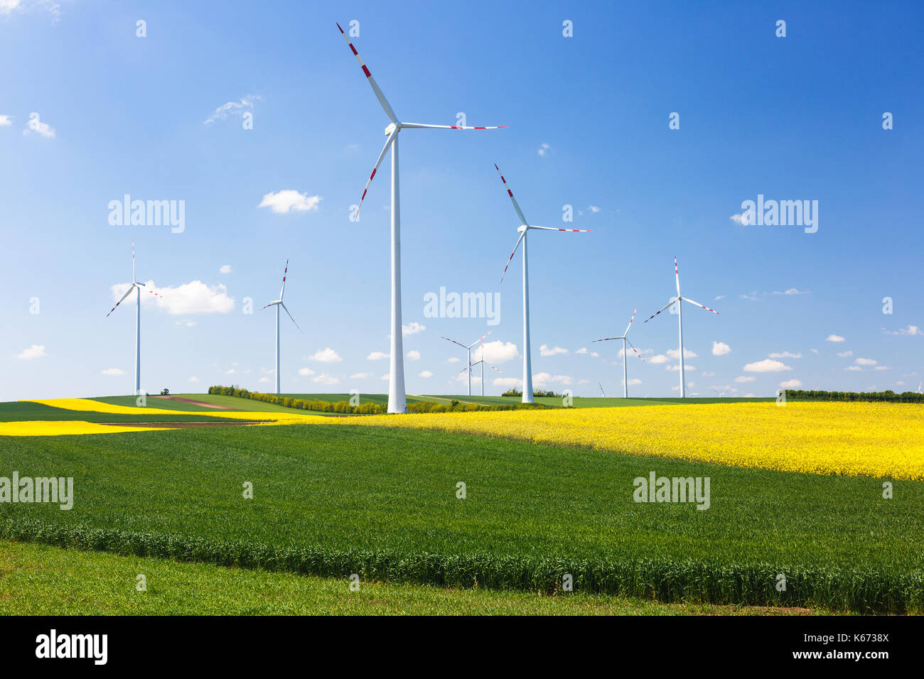 Wind farm with spinning wind turbines amidst agricultural land of