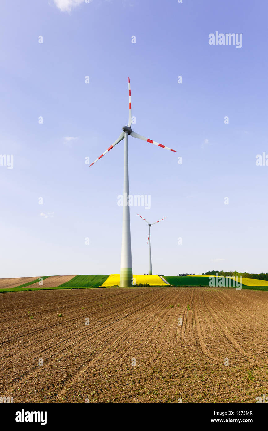 Wind farm with spinning wind turbines amidst agricultural land of