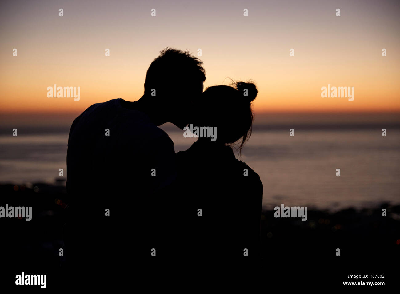 Couple kissing by the sea at sunset, silhouette Stock Photo - Alamy