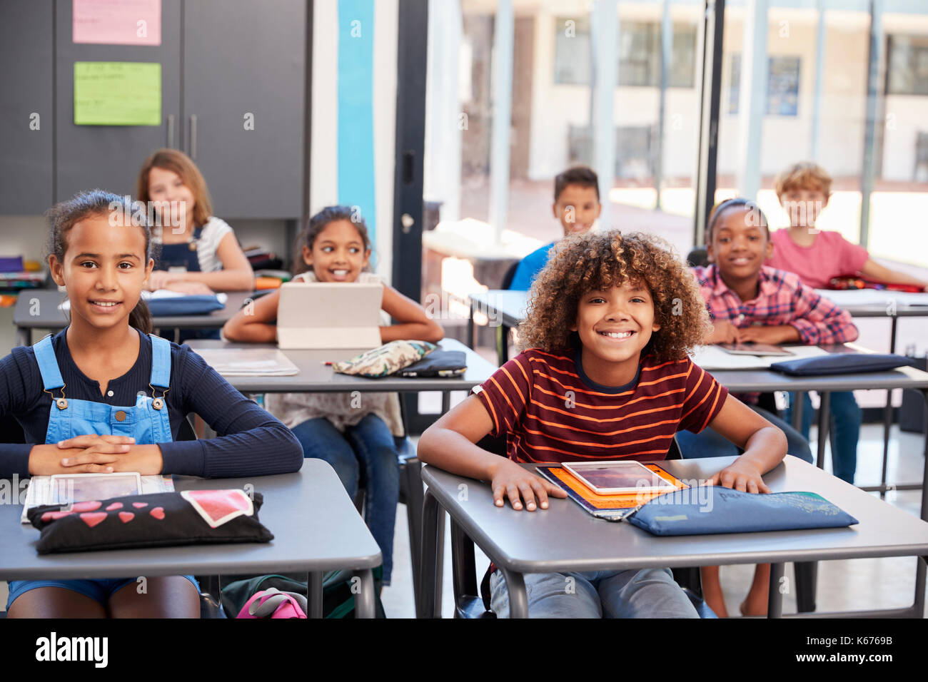 Portrait Of Elementary School Pupils Sitting At Their Desks Stock