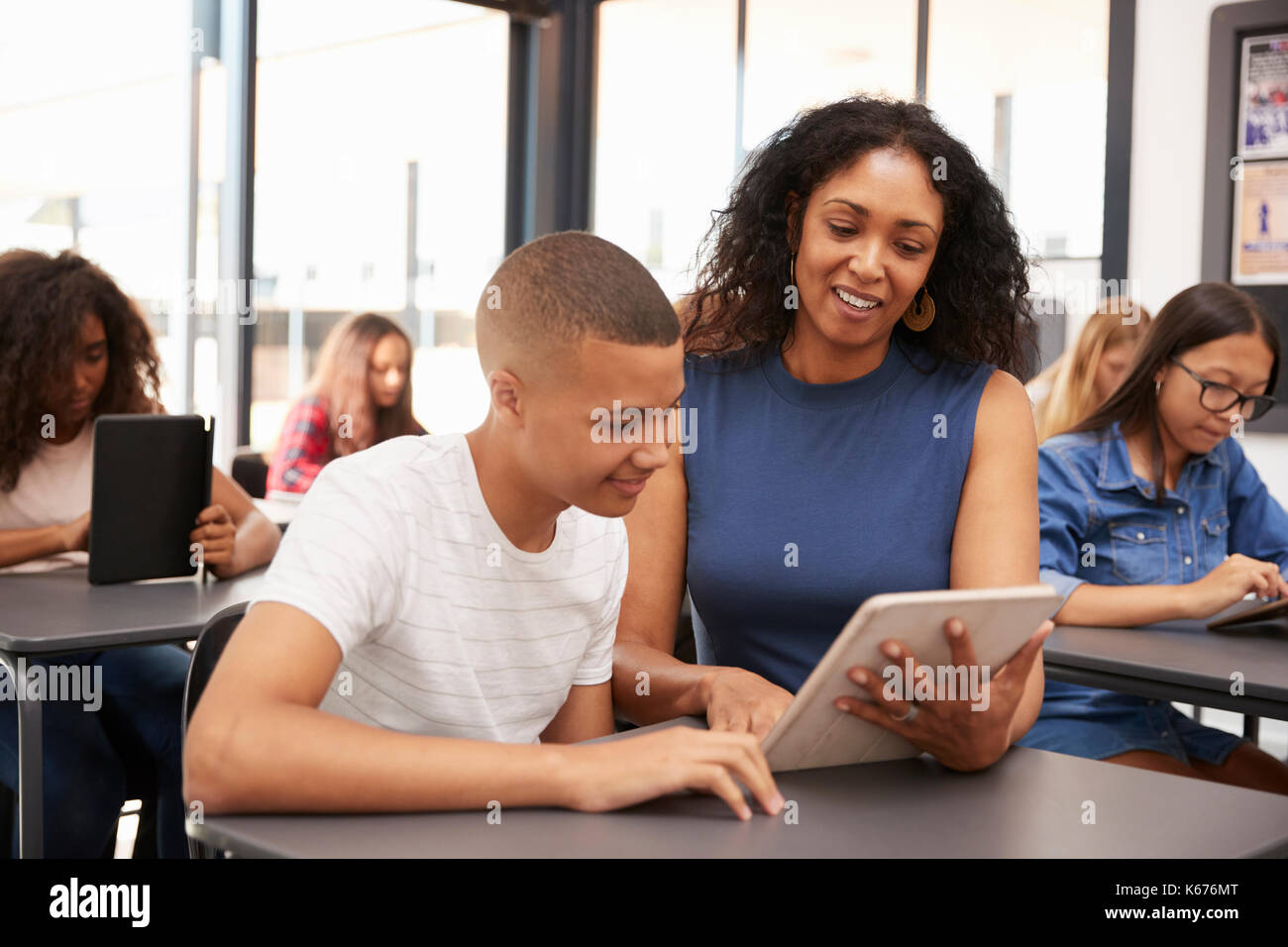 Teacher helping teenage schoolboy with tablet computer Stock Photo