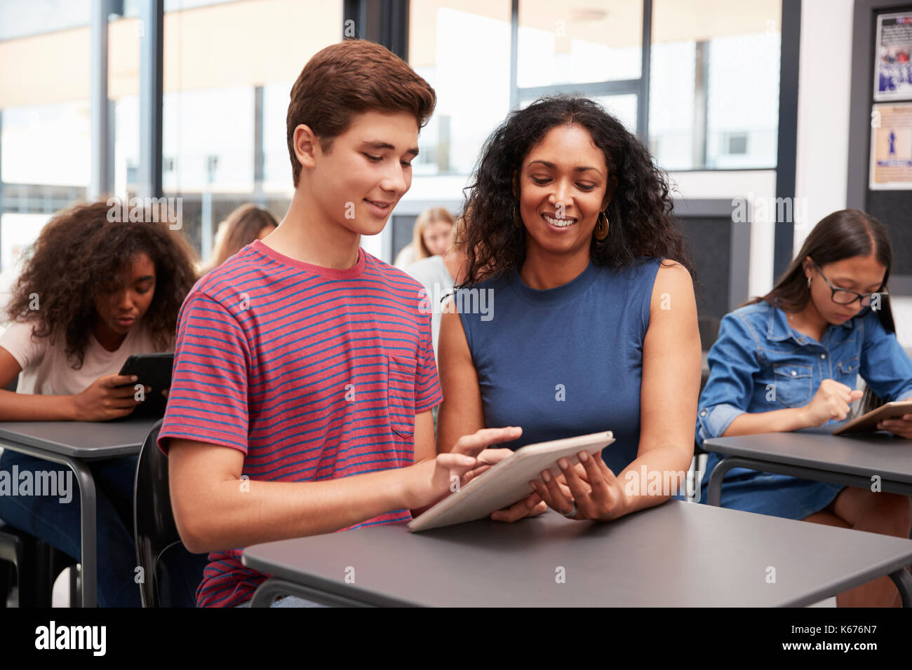Teacher helping teenage schoolboy with tablet computer Stock Photo - Alamy