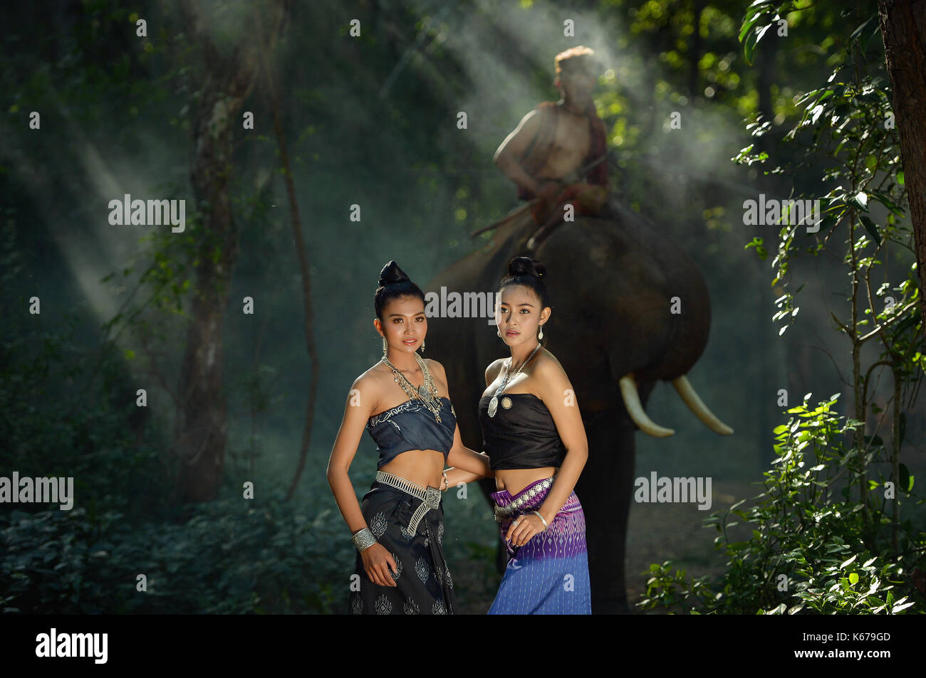 Two women in traditional Thai clothing with a mahout riding an elephant, Thailand Stock Photo
