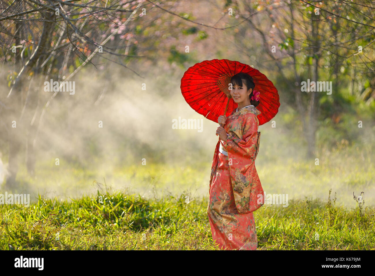 Woman in traditional Japanese clothing in a cherry blossom orchard