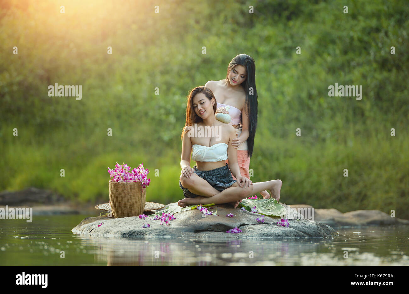 Woman giving her friend a massage by the river, Thailand Stock Photo