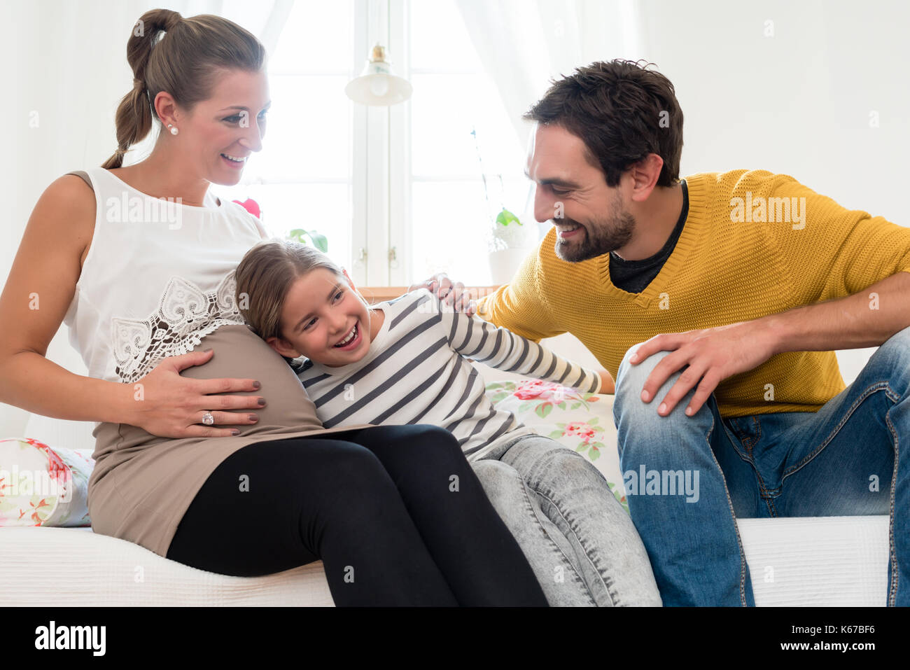Little girl listening at belly of her pregnant mom Stock Photo