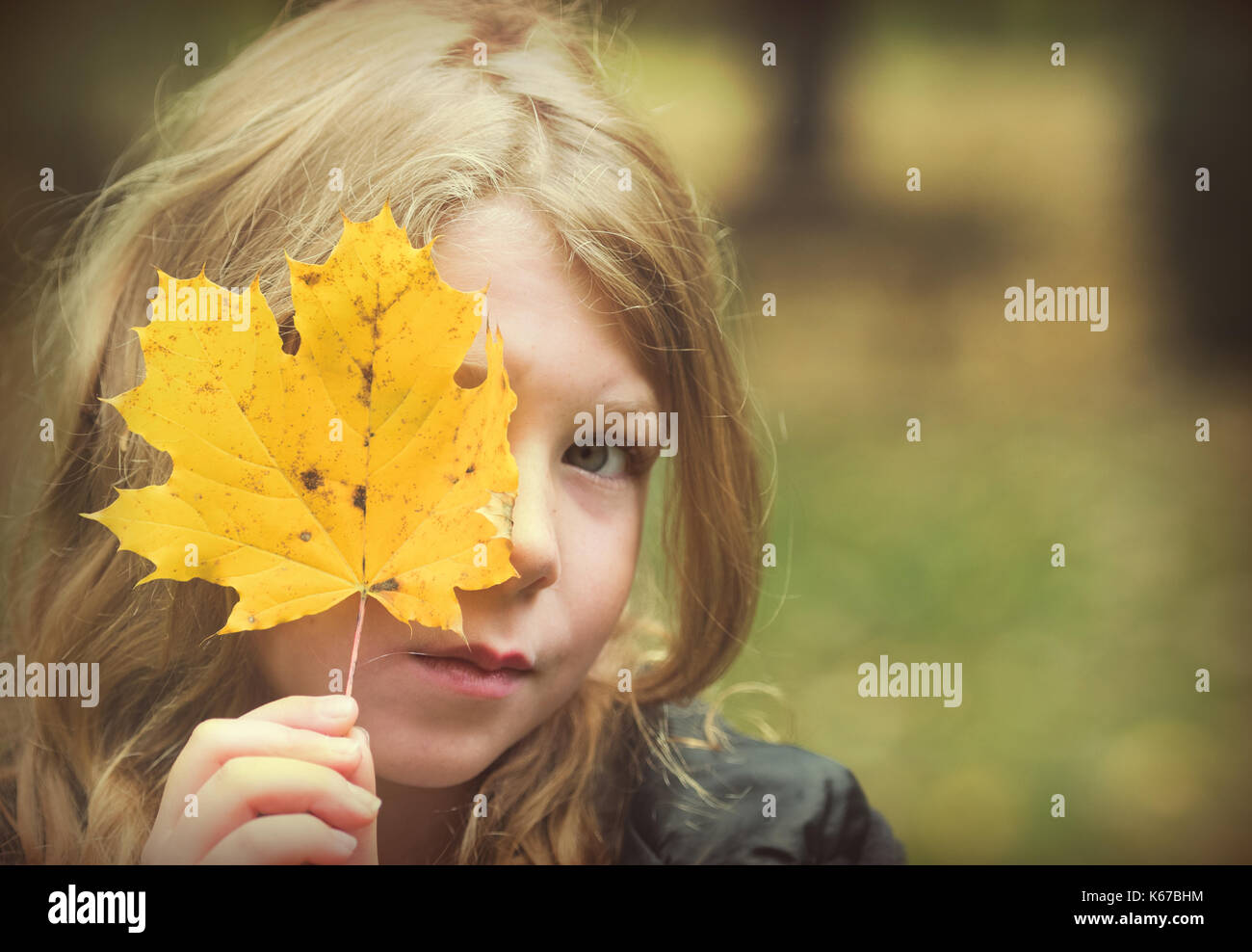 Girl holding a leaf in front of her face Stock Photo - Alamy