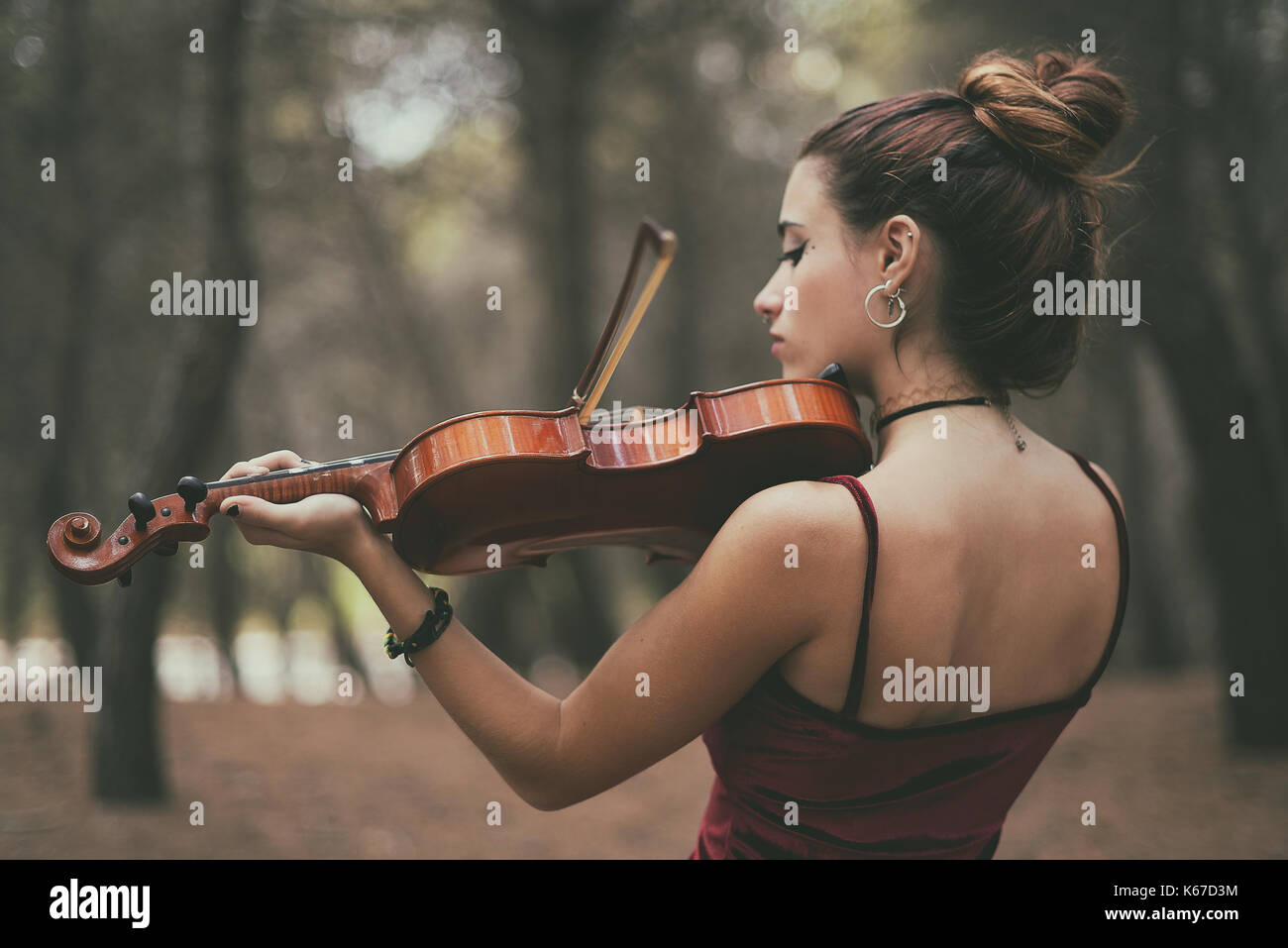 Girl standing in forest playing the violin Stock Photo - Alamy
