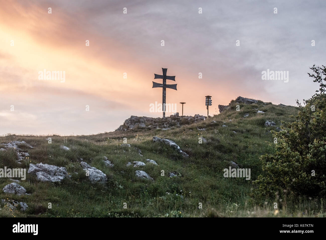 Klak hill eith cross, mountain meadow and limestone stones in Mala Fatra mountains in Slovakia during sunset with colorful sky Stock Photo