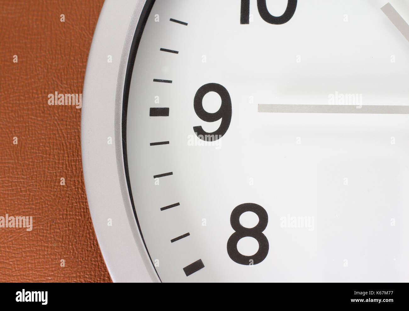 close up of an analog clock face and hands against a brown leather