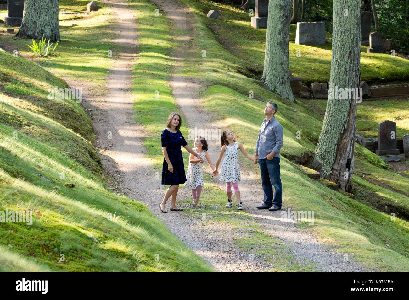 parents holding hands with two daughters walking and exploring on a path looking around Stock Photo
