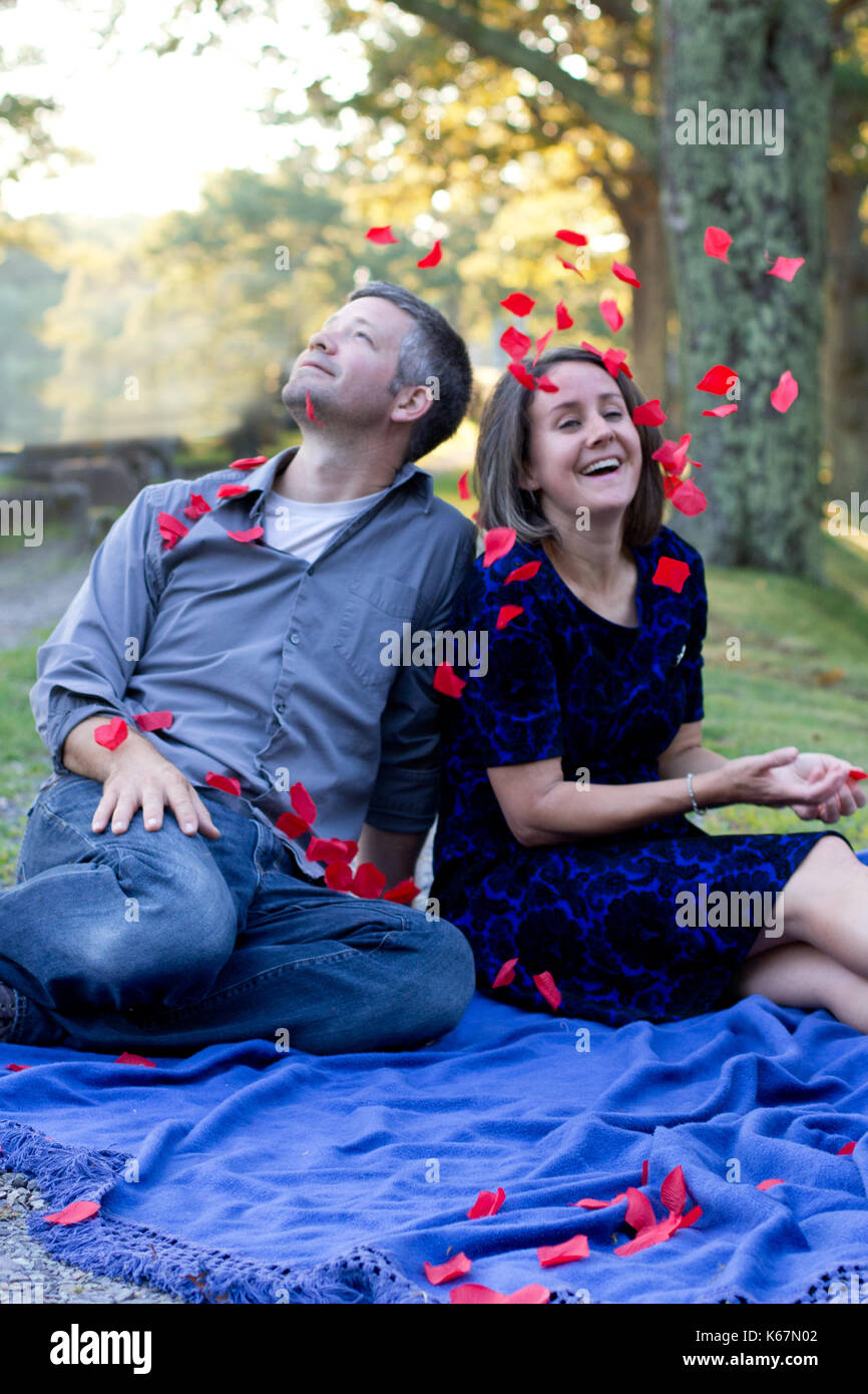 happily married couple smile and laugh as roses fall on them Stock Photo