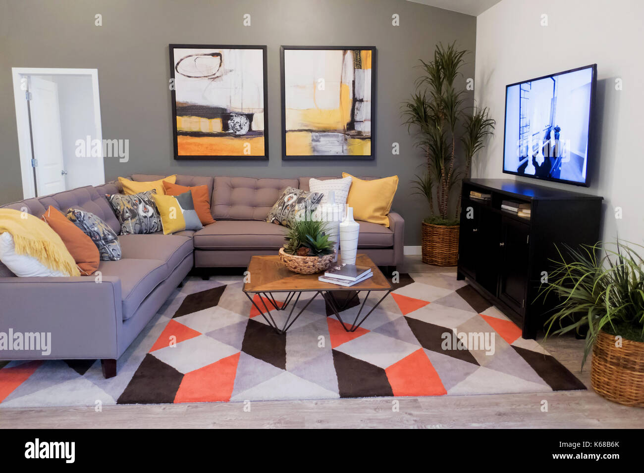 A gray sectional couch on a colorful rug near a TV stand and side table  Stock Photo - Alamy