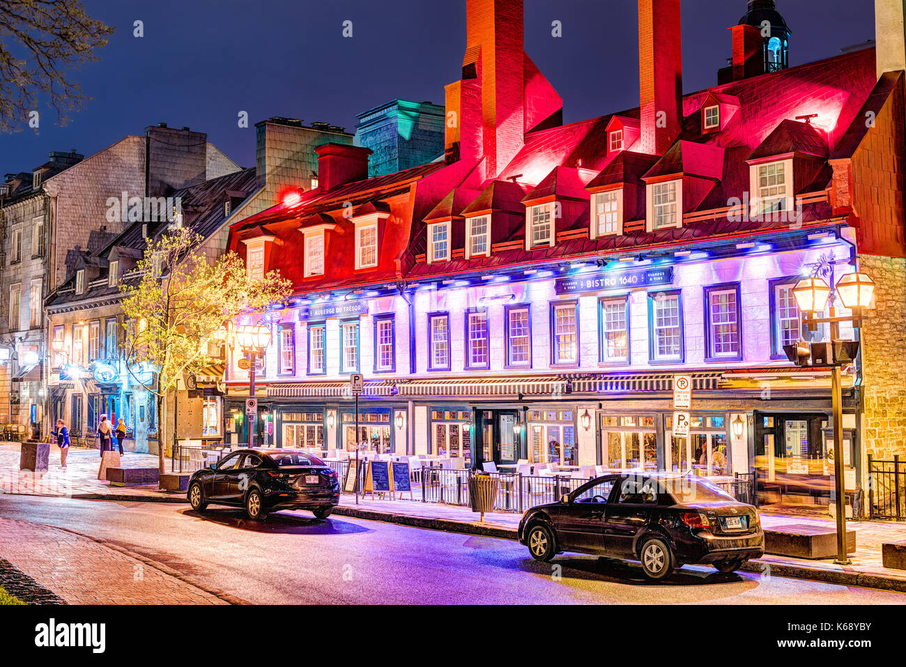 Quebec City, Canada - May 30, 2017: Old town Sainte Anne street with red colorful restaurant building by place D'arms park with people walking at nigh Stock Photo