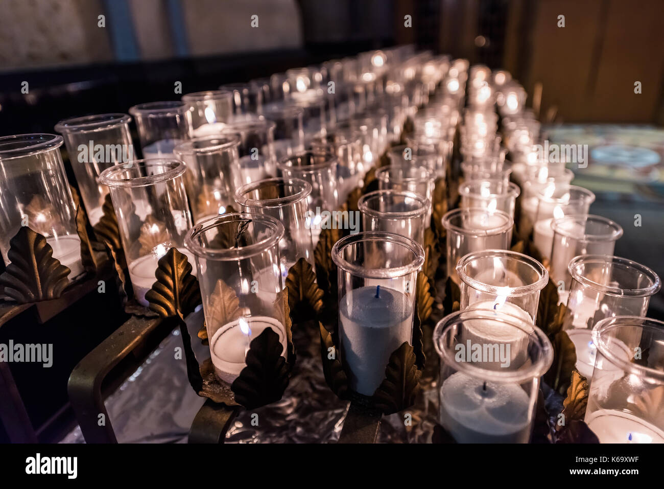 Closeup side pattern of many white religious votive candles with yellow