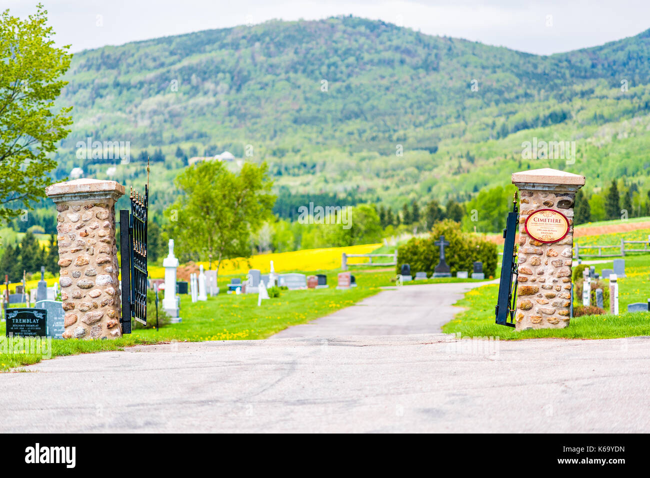 Les Eboulements, Canada - June 2, 2017: Presbytere Des Eboulements cemetery in Charlevoix region of Quebec with open gate, tombstone, graves, mountain Stock Photo