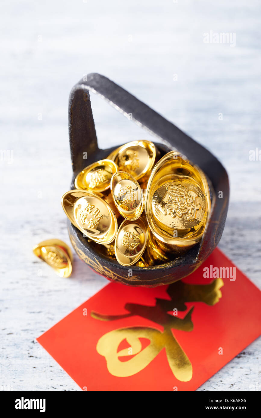 Chinese New Year - Gold sycee (Foreign text means wealth) and red packet (Foreign text means spring season) on white painted wood table Stock Photo