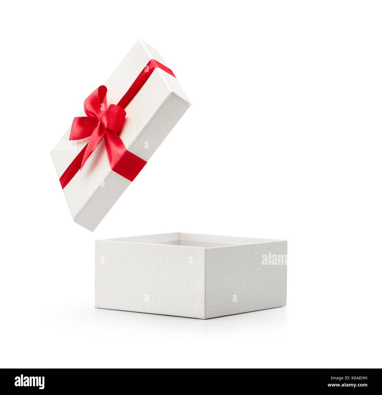A gift wrapped in plain red paper with a raffia bow are set on a white  background. Horizontal shot. Isolated on white Stock Photo - Alamy