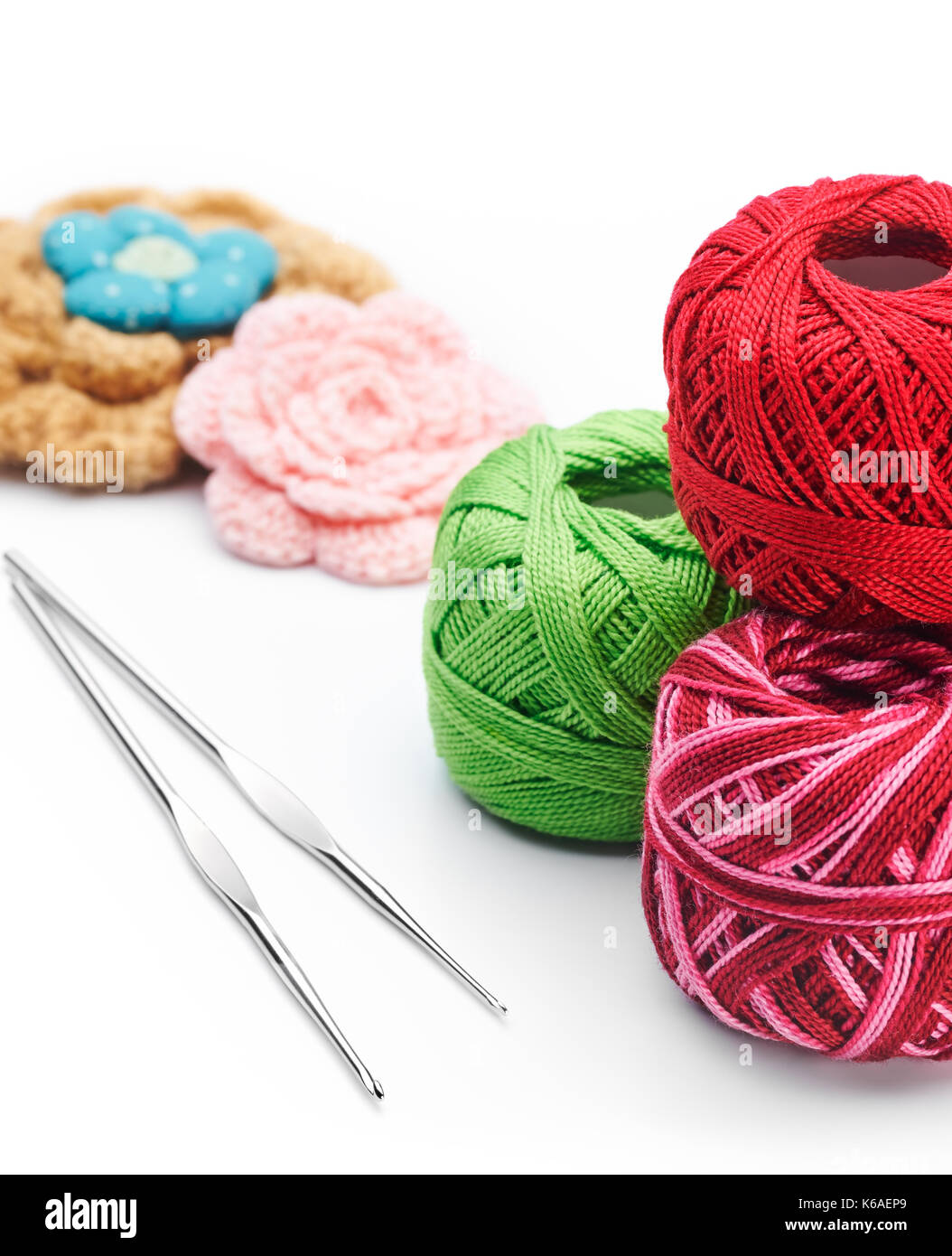 Yarn, hook and handmade crochet flowers. Needlework accessories on white background Stock Photo