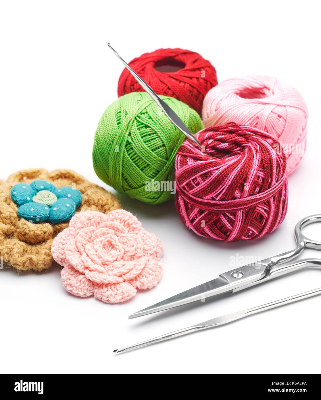 Yarn, scissor and handmade flowers. Needlework on white background Stock Photo -