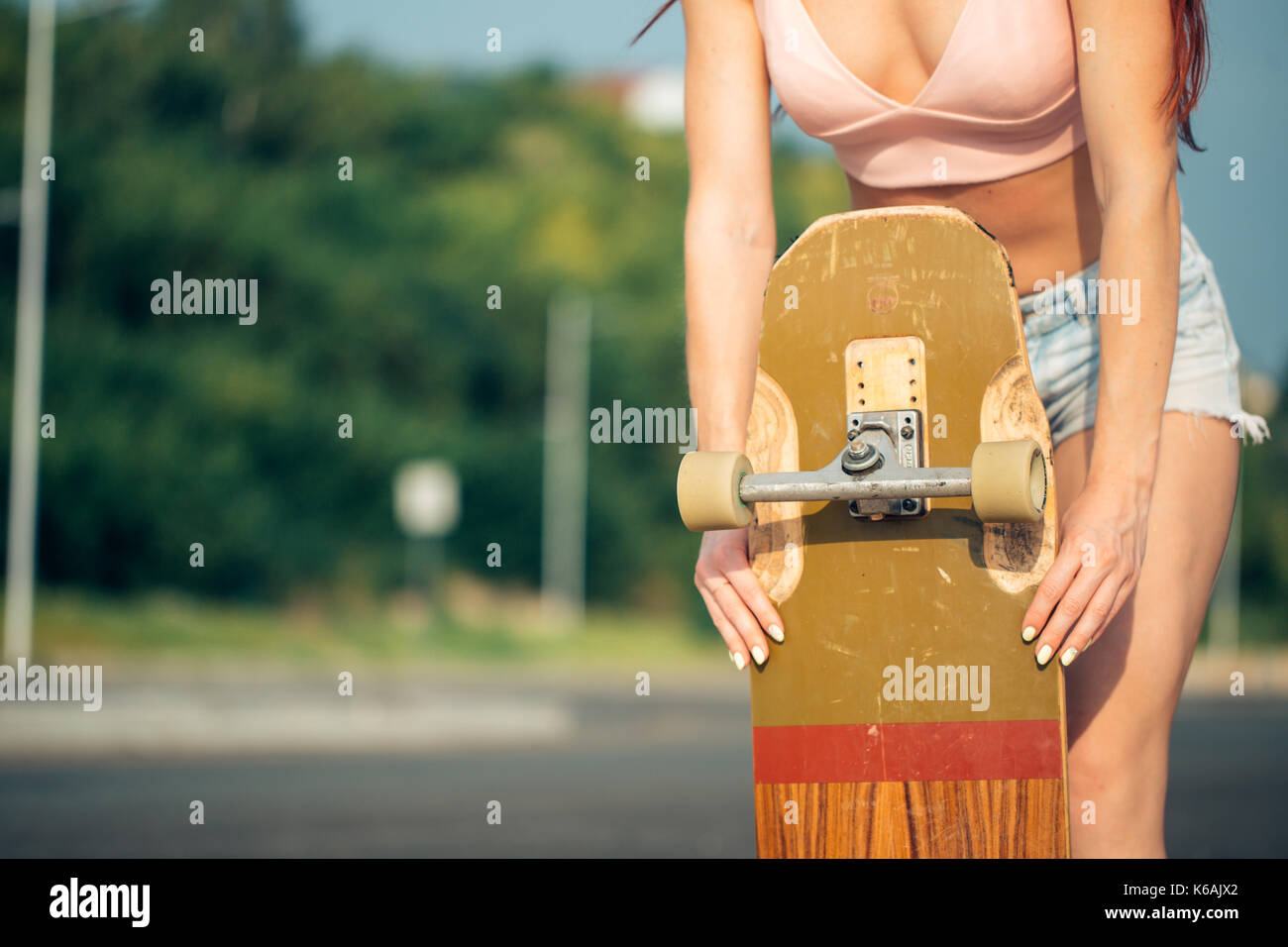 acticity and summer holiday concept - close up of female hand holding skateboard. Stock Photo