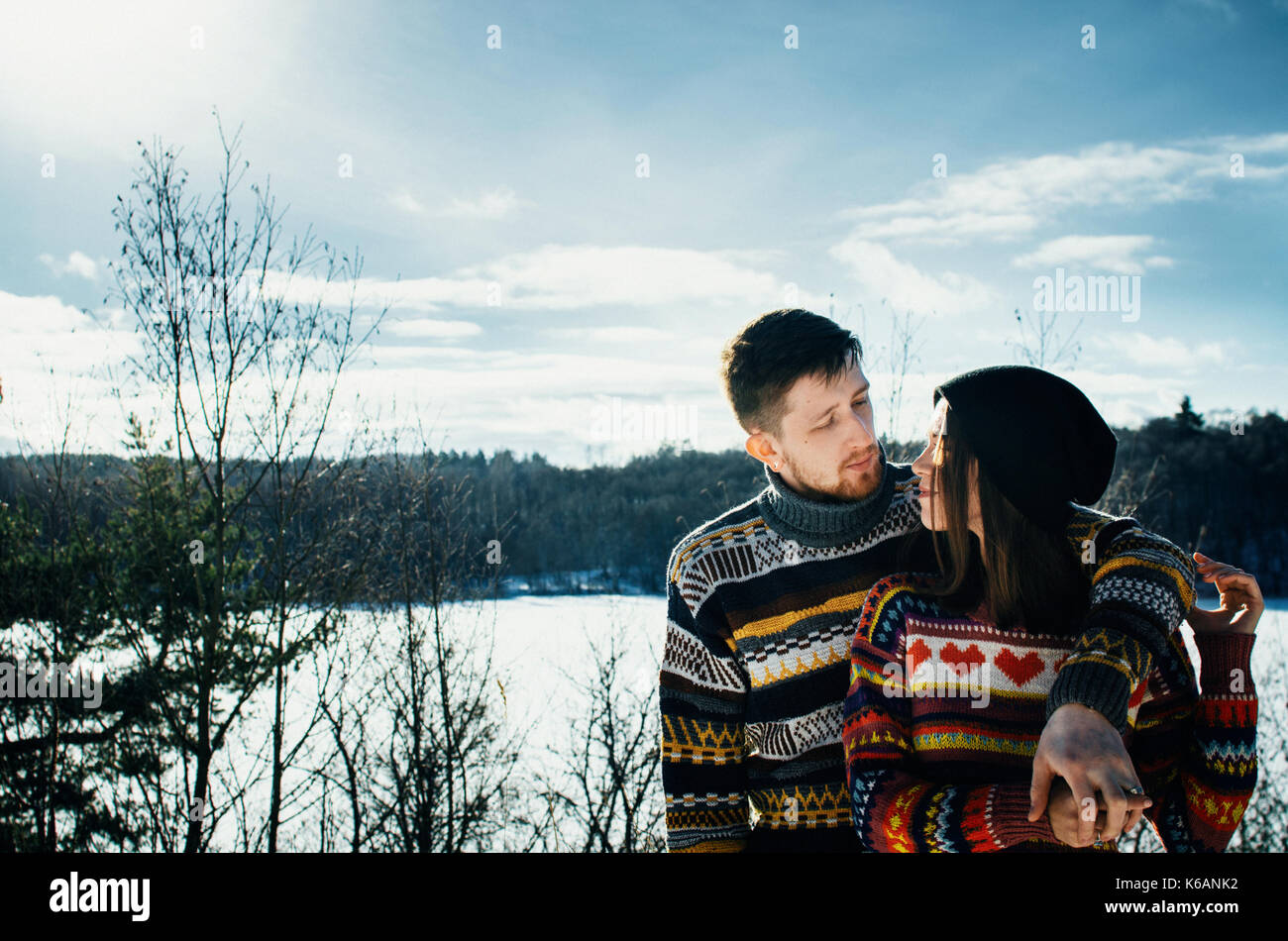 Joyful cute couple embraces. Young man in a sweater hugs a girl from behind background in winter. The concept of a successful relationship and happy m Stock Photo