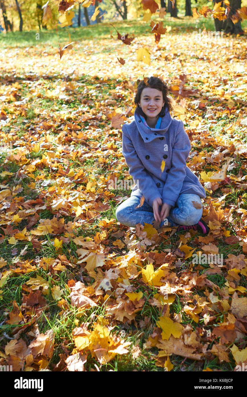 happy young teen girl in autumn scenery throwing leaves Stock Photo