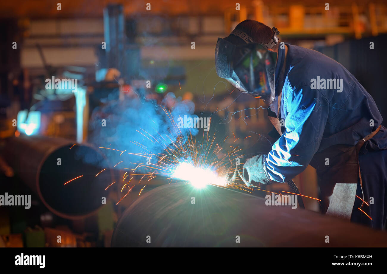Welder performs welding large diameter pipe inside plant Stock Photo