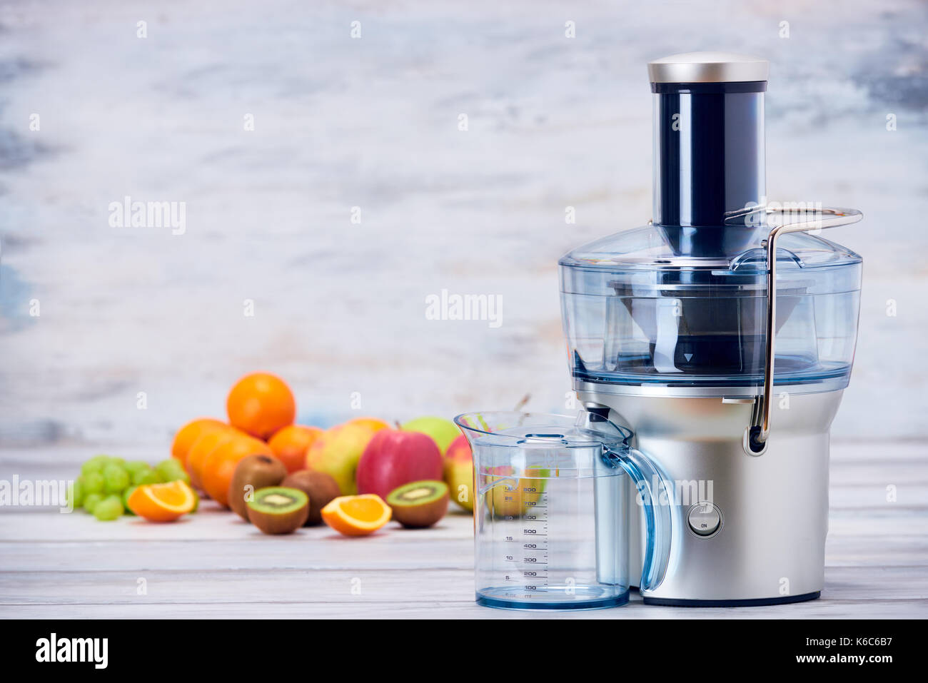 Modern electric juicer and various fruit on kitchen counter, healthy lifestyle detox concept