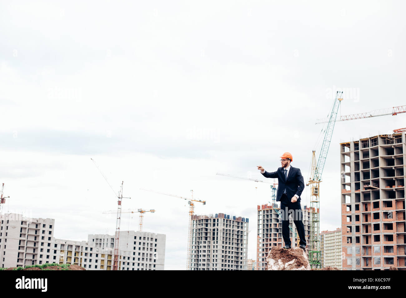 senior builder in hardhats pointing workers outdoors Stock Photo