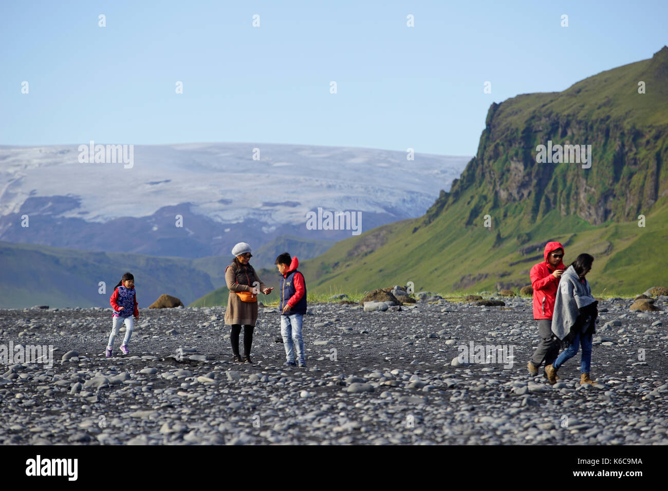 Tourists at Reynisfjara beach, one of the most popular sight in Iceland, and the ice cap covering the Katla volcano. Stock Photo