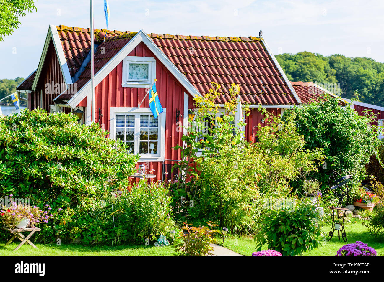 Karlskrona, Sweden - August 28, 2017: Travel documentary of city gardens. Red vintage coastal cabin with flowers and shrubbery in the garden. Stock Photo