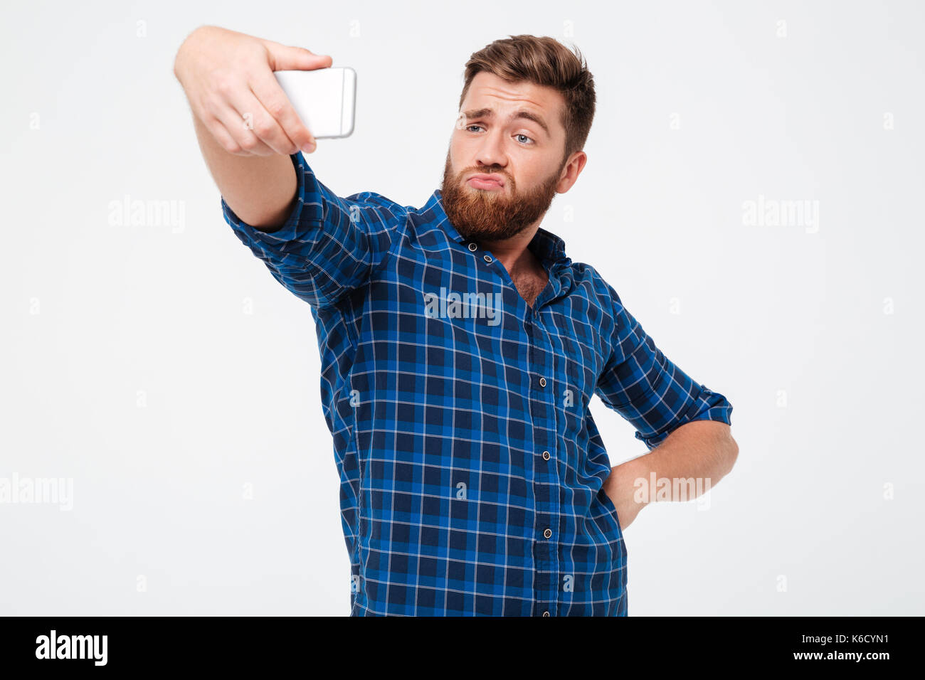 Funny bearded man posing and making selfie on his smartphone over gray ...