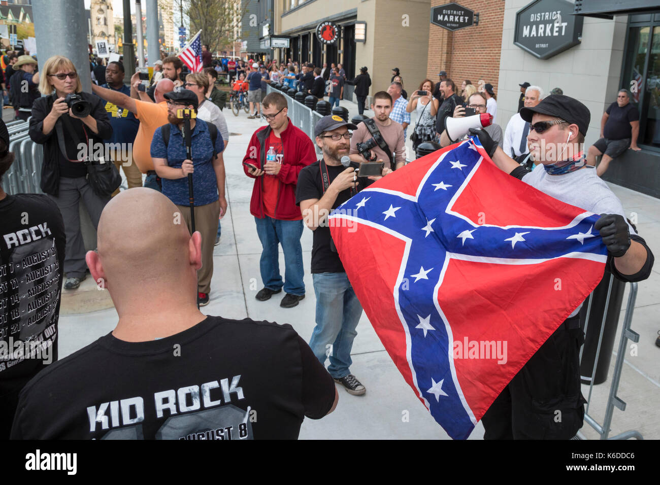 Detroit, Michigan USA - 12 September 2017 - As the new Little Caesars sports/concert arena opened, people protested the selection of Kid Rock for the arena's inaugural concert. A Kid Rock supporter displays a Confederate flag to protesters. The singer has displayed the Confederate flag at some of his past concerts; protesters felt that was not an appropriate message for the arena, which was partially paid for with taxpayer dollars. Besides concerts, the arena will house the Detroit Red Wings and Detroit Pistons teams. Stock Photo