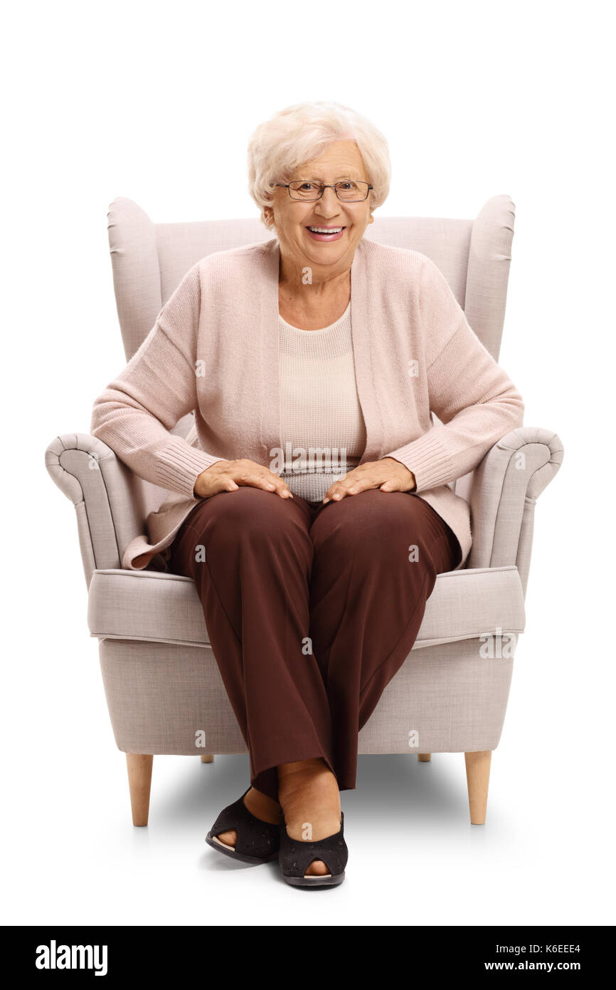 Elderly woman sitting in an armchair and smiling isolated on white ...