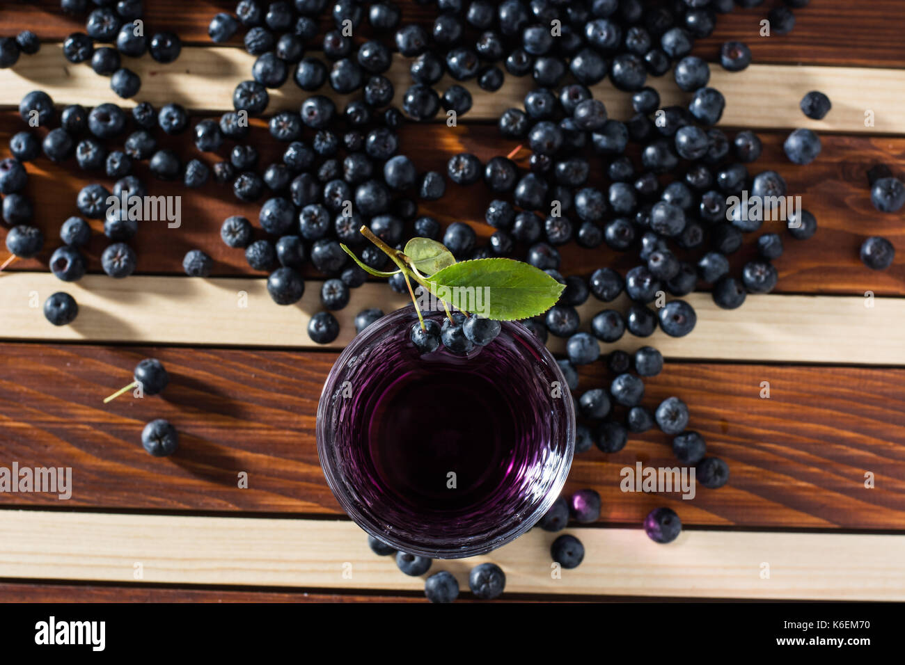 Aronia spilled on wooden table with glass of aronia juice Stock Photo