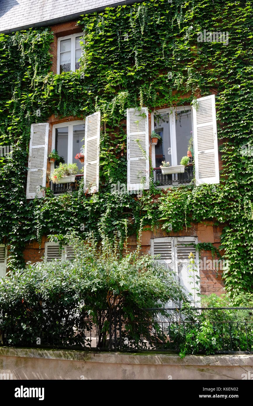 An urban garden in a house in Rue Lepic in Montmartre, Paris with beautiful shutters, flowers and green ivy on the walls. Stock Photo
