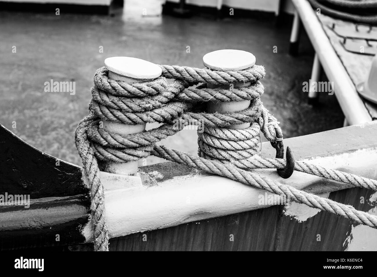 Close-up nautical knot rope tied around stake on boat or ship boat mooring rope. B&W Picture Stock Photo