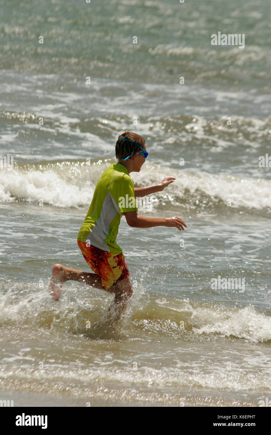 BOY PLAYING IN WAVES IN GULF OF MEXICO, BOLIVAR PENINSULA, TEXAS Stock Photo