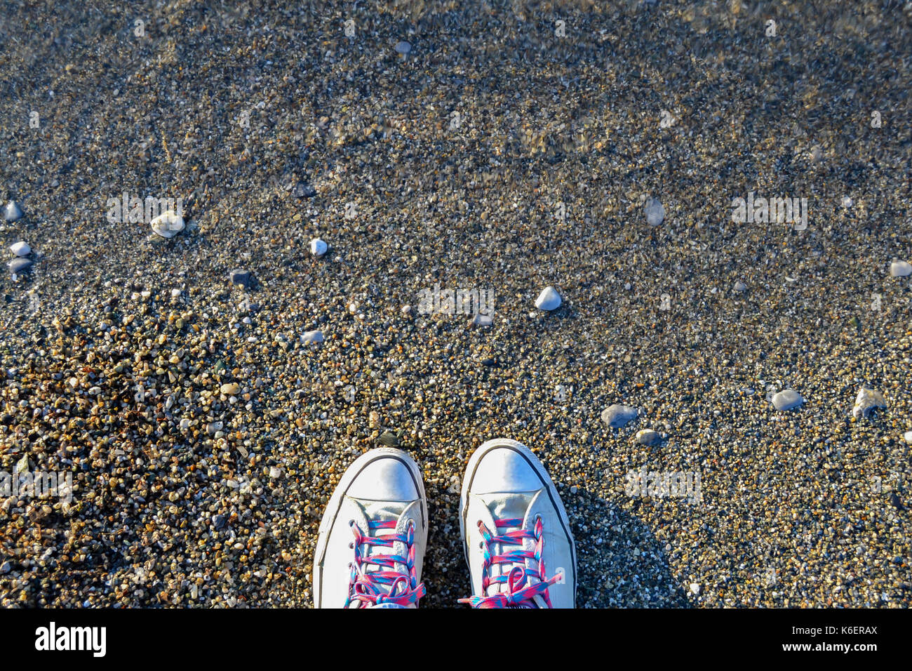 Concept with blue sneakers on bright sea pebbles with space for the text. Stock Photo
