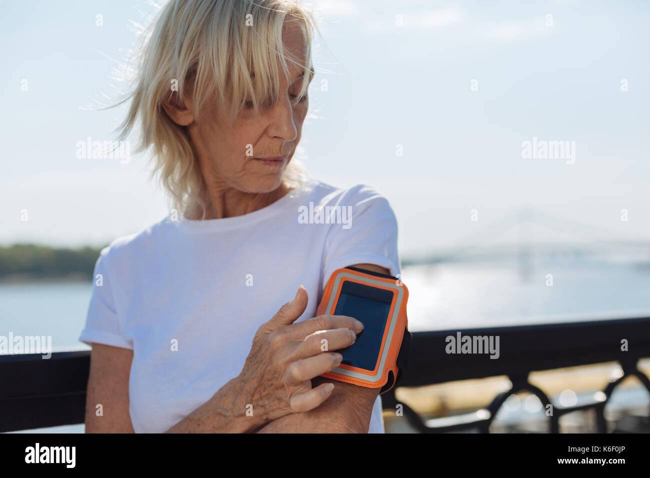 Athletic elderly lady tracking distances with phone in arm band Stock Photo