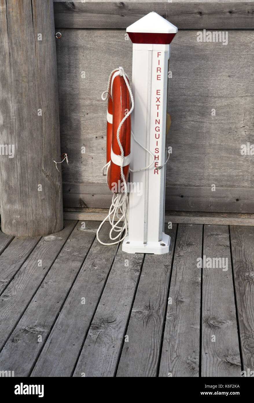 Side View of an Orange Life Buoy on a Fire Extinguisher Post on a dock Stock Photo