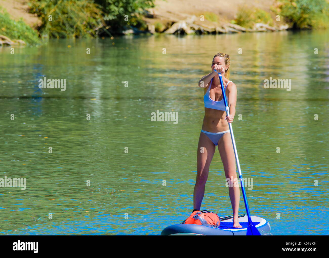 Young teenager girl in swimsuit holding supboard on the beach. AI