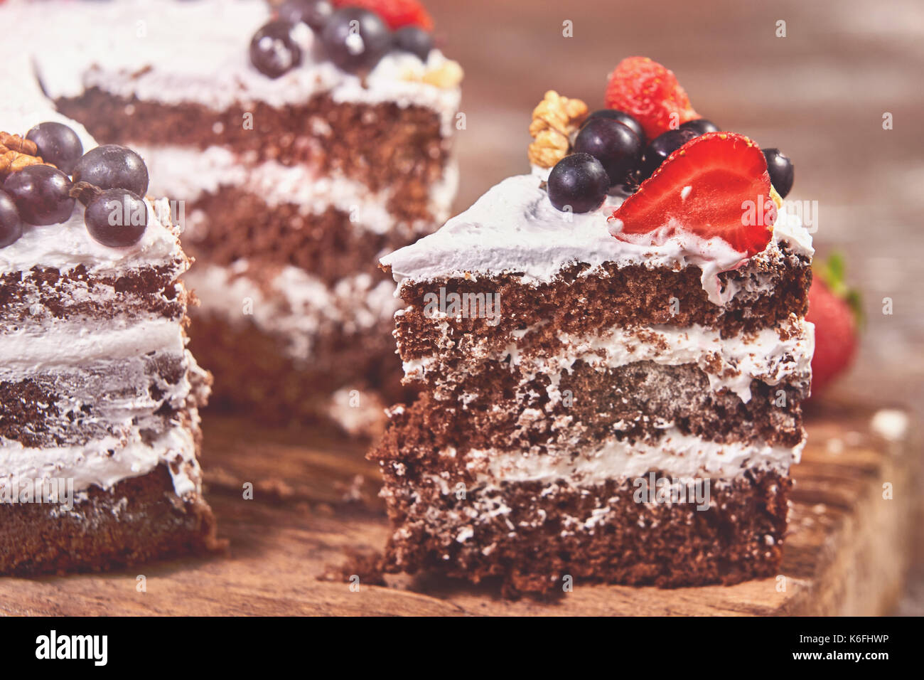 a cut of cake with whipped cream and strawberry fruits on wood table ...