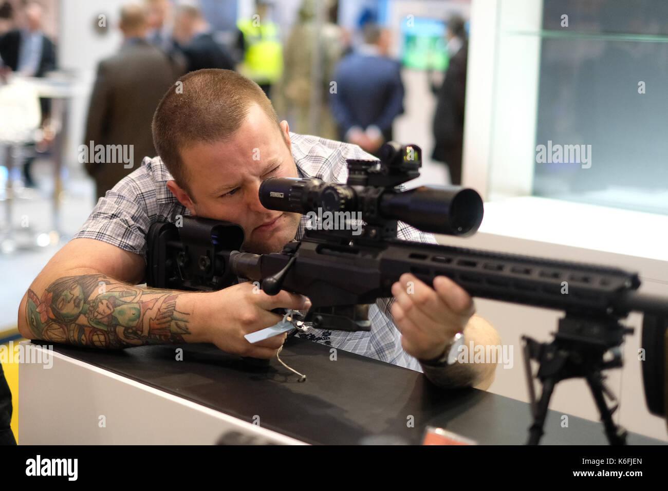 A visitor looks through a sight on a sniper rifle during the Defence Systems and Equipment International arms fair at the ExCel centre in London. Stock Photo