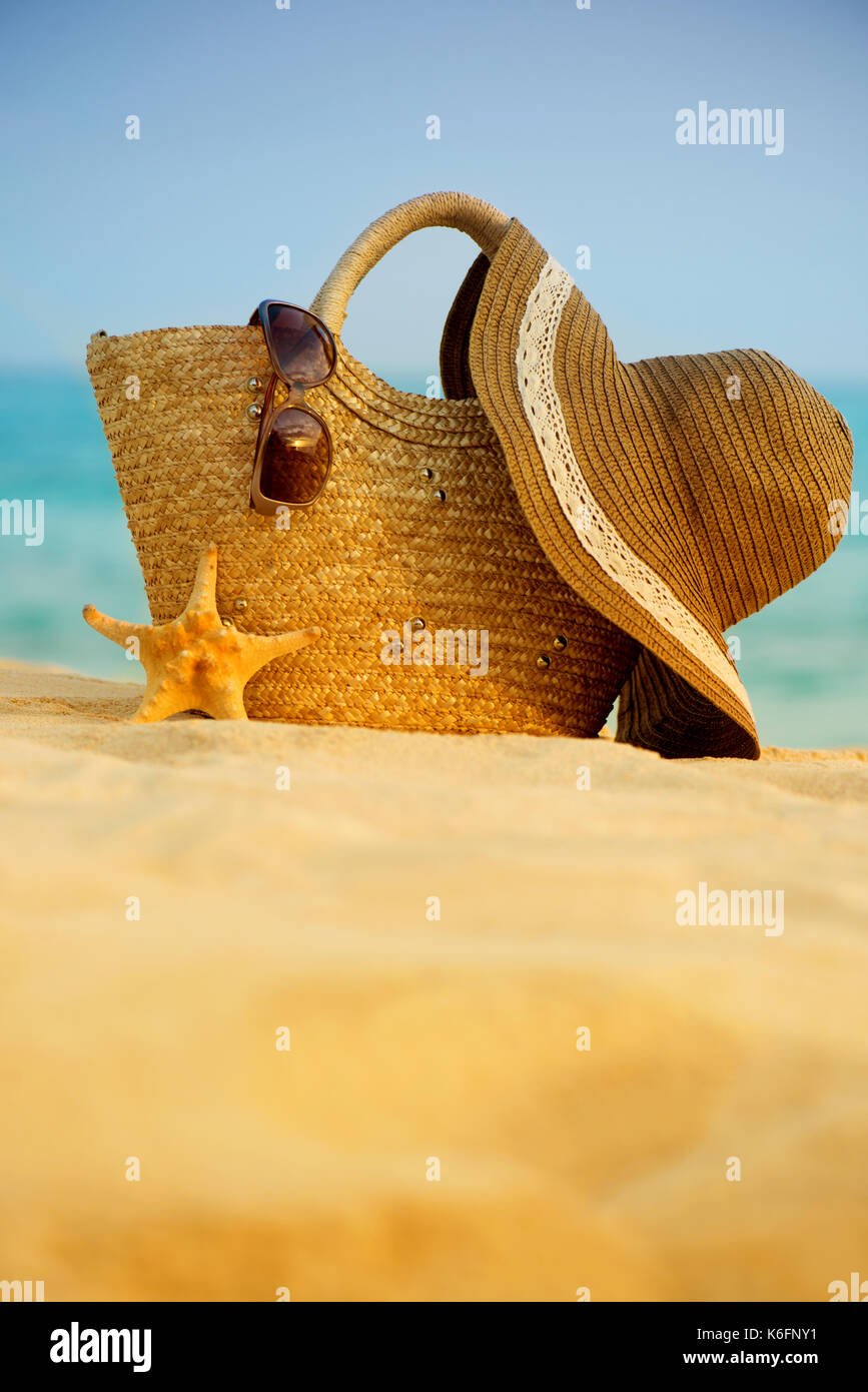 Vintage summer wicker straw beach bag, sun glasses, hat near swimming pool,  tropical background. Stock Photo