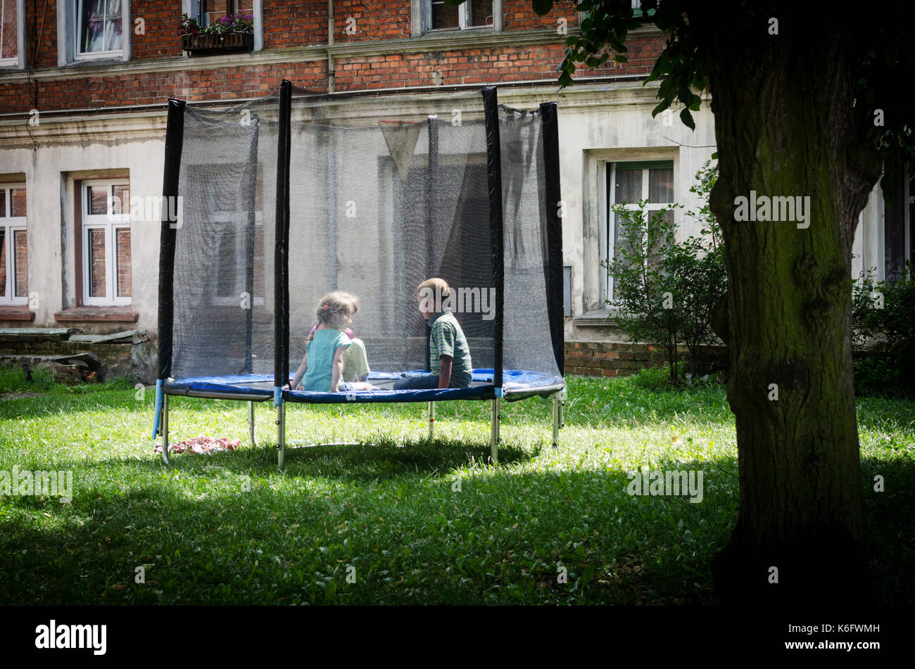 Kids playing on the trampoline outside in the garden on a sunny day Stock Photo