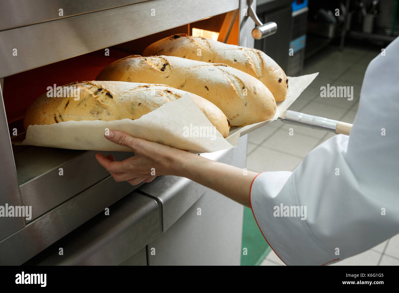 https://c8.alamy.com/comp/K6G1G5/hands-of-a-baker-getting-hot-bread-loafs-ot-of-the-oven-on-a-small-K6G1G5.jpg