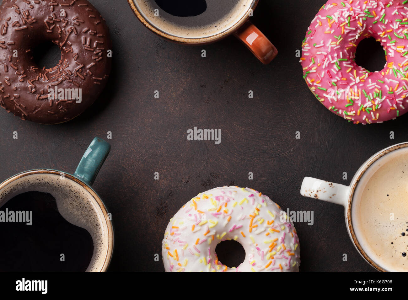 Coffee cups and colorful donuts on stone table. Top view with copy ...
